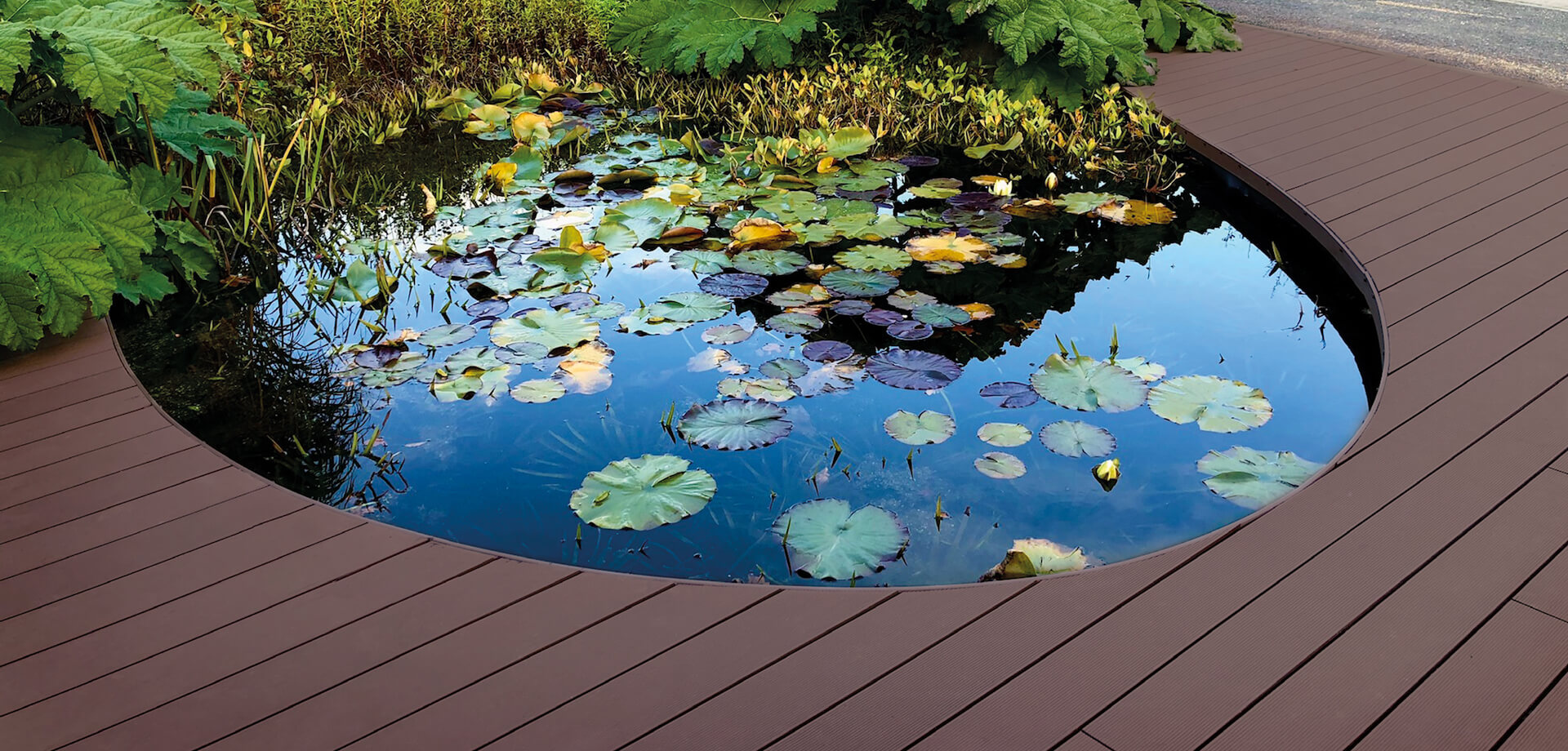 HD Deck® XS in a walnut finish installed around pond in landscaped gardens