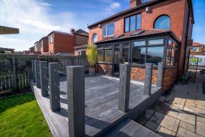 Black composite decking in back garden of red brick house
